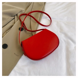 Detailed top view of red semi-circular saddle bag on khaki trench coat background
