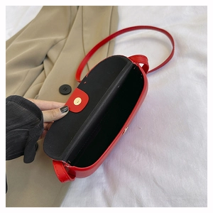 Detail view of red faux leather saddle bag with magnetic closure and black inner lining