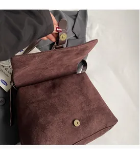 Detail of magnetic snap closure on brown vintage messenger bag with matte finish