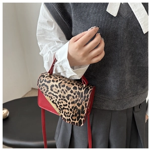 Détail du sac rouge en cuir avec rabat léopard et boucle triangulaire dorée élégante