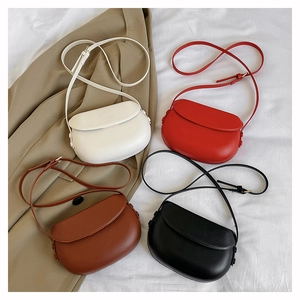 Minimalist semi-circular saddle crossbody bags in four colors on a khaki blazer background