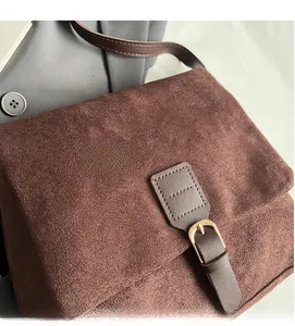 Close-up of retro brown suede tote bag with gold buckle on a grey blazer background