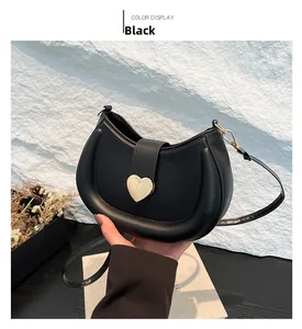 Close-up of black crescent hobo bag with gold heart buckle and matte leather texture