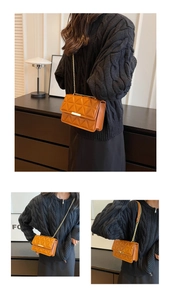 Detail of orange quilted crossbody bag featuring gold chain strap and metal clasp