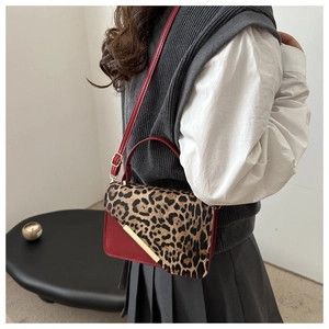 Détail du sac à bandoulière en cuir rouge avec imprimé léopard et accents dorés