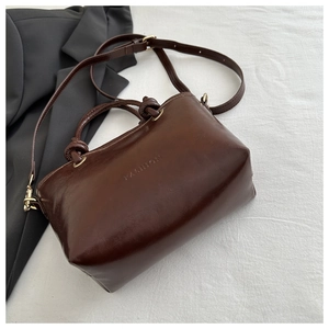 Gros plan du sac oreiller marron foncé avec gaufrage FASHION et boucles dorées