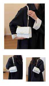 Close-up of a white quilted crossbody bag with gold chain strap and metal bar detail