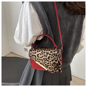 Détail du sac rouge en cuir avec rabat imprimé léopard et barre dorée décorative