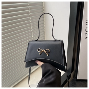 Détail du sac à main noir mat avec boucle nœud dorée et fine bandoulière