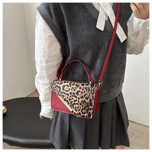 Détail d'un sac à main en cuir rouge à imprimé léopard avec barre dorée et bandoulière