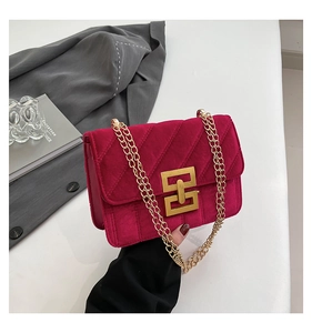 Détail d'un sac bandoulière en velours fuchsia avec chaîne dorée et matelassage