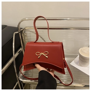 Macro shot of the red matte leather small square bag with a golden bow-shaped buckle