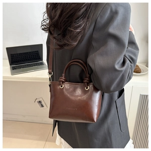 Close-up of brown leather bucket bag with FASHION embossed logo and gold metal hardware