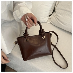 Détail d'un sac seau vintage marron foncé avec anses nouées et logo fashion gaufré