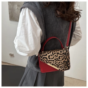 Détail du sac rouge avec rabat léopard et garniture en métal doré porté par modèle