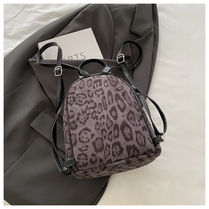 Nahaufnahme des Mini-Rucksacks mit Leopardenmuster und Lederriemen auf grauem Blazer