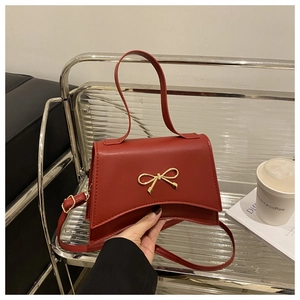 Close-up of a red bow-tie lady handbag with golden hardware and curved base