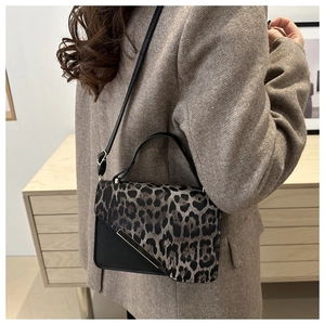 Détail du rabat léopard et du fermoir doré sur un petit sac à main en cuir noir