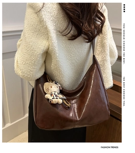 Detail of dark brown tote bag featuring a plush leopard-print cat pendant and leather texture