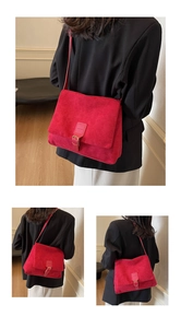 Macro detail of red suede shoulder bag featuring a vintage flap and metal buckle design