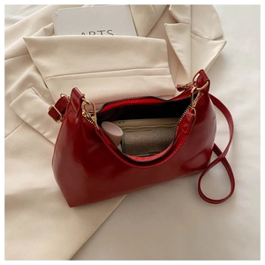 Macro shot of red patent leather crescent bag interior holding daily essentials