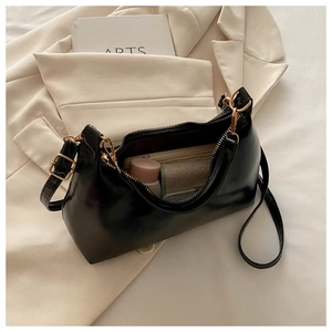 Internal view of black glossy shoulder bag showing storage space for makeup and wallet