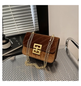 Détail du sac bandoulière en velours marron avec boucle géométrique dorée et chaîne