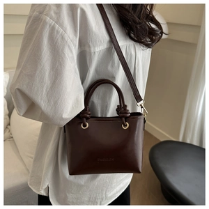 Détail du sac à bandoulière marron foncé avec poignée nouée et anneaux métalliques dorés