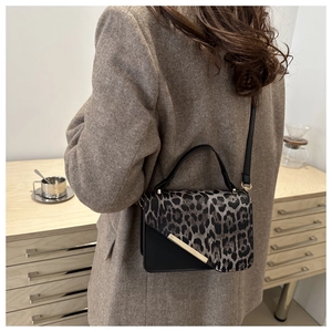Détail du sac bandoulière léopard avec bordure dorée porté sur un manteau marron élégant