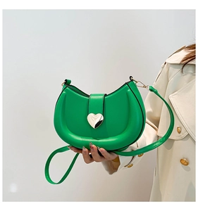 Detail of bright green leather saddle bag with silver heart buckle on beige coat