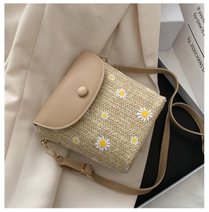 Dettaglio del ricamo a margherita su borsa in paglia beige con patta in pelle kaki