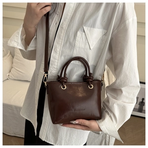 Close-up of a dark brown crossbody bucket bag with FASHION engraving and gold hardware