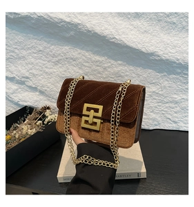 Détail du sac bandoulière en velours marron avec texture matelassée et fermoir doré en G