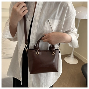 Detail of dark brown leather handbag with FASHION embossing and gold metal hardware