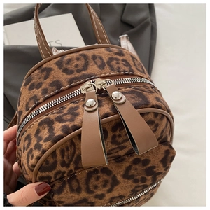 Details des Leopard-Rucksacks mit braunen Leder-Zippern und Metall-Nietenverzierung