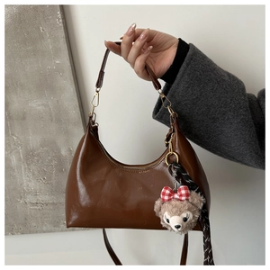Detail of dark brown hobo bag featuring gold zipper and a cute plush bear pendant accessory