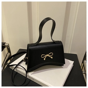 Close-up of black matte leather handbag with a gold bow metal clasp and curved base