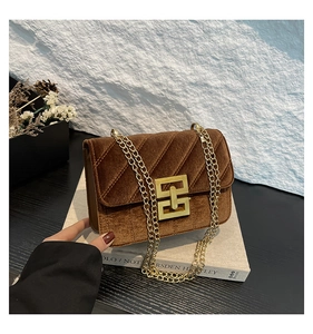 Détail du sac bandoulière en velours marron avec texture matelassée et chaîne dorée