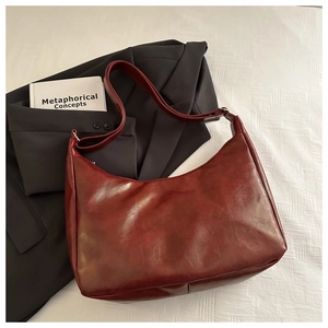 Close-up of deep red vintage hobo bag with adjustable strap and smooth texture