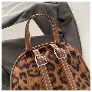 Detail des Leoparden-Rucksacks mit braunem Ledergriff und weißer Kontrastnaht im Fokus