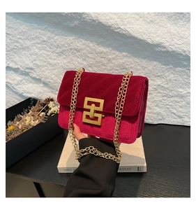 Gros plan détaillé du sac à bandoulière en velours rouge avec texture matelassée et fermoir doré