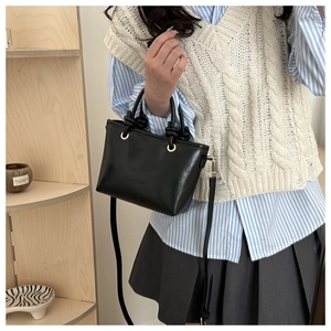 Detail of vintage black PU leather handbag with knotted handle and gold metal hardware