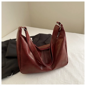 Detailed close-up of dark wine red retro leather tote bag on soft white bedding