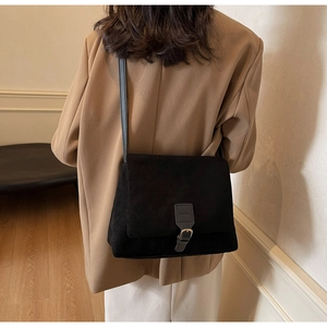 Model wearing black matte faux suede crossbody bag with flap cover for daily commute style