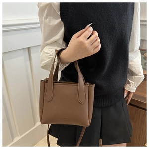 Detail of brown litchi pattern leather bucket bag with top handles and adjustable strap