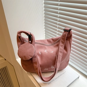 Detailed view of pink corduroy shoulder bag with letter embroidery and small pouch charm