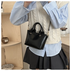 Close-up of black leather bucket bag with FASHION embossing and gold hardware
