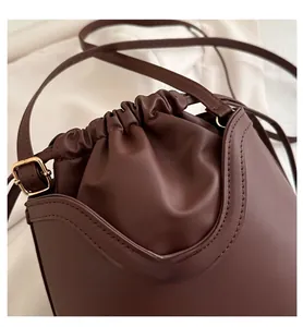 Detail of vintage brown leather bucket bag with drawstring closure and fine stitching