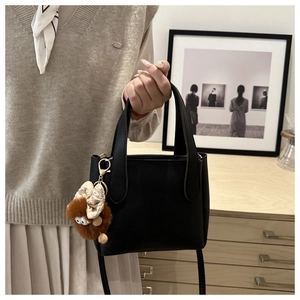Detail of black pebbled leather mini bucket bag featuring a cute plush eye charm