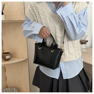 Detail of black leather tote bag with unique knotted handle and gold metal eyelets